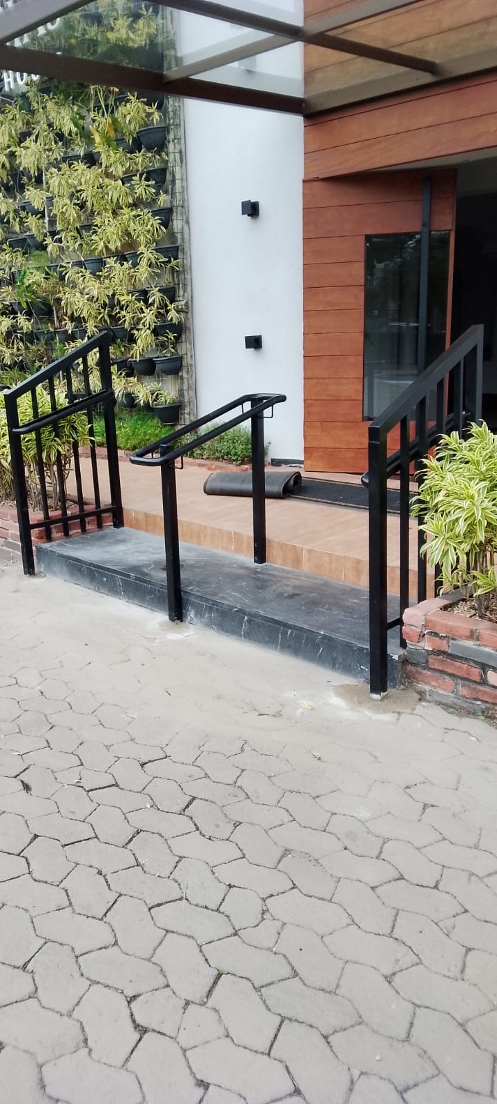 Entrada de prédio comercial com guarda-corpos e corrimãos metálicos pretos