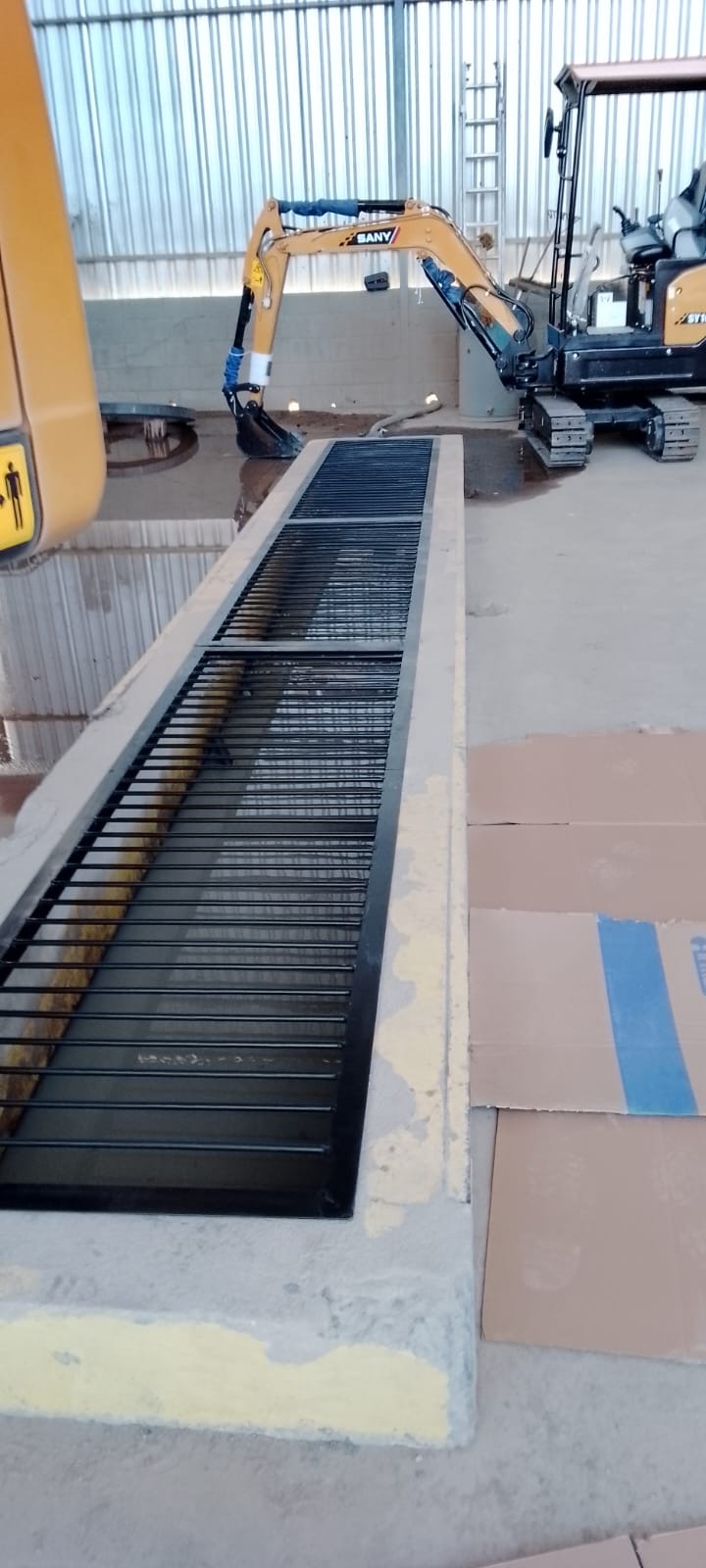 Grelha metálica preta instalada sobre canaleta em pátio industrial