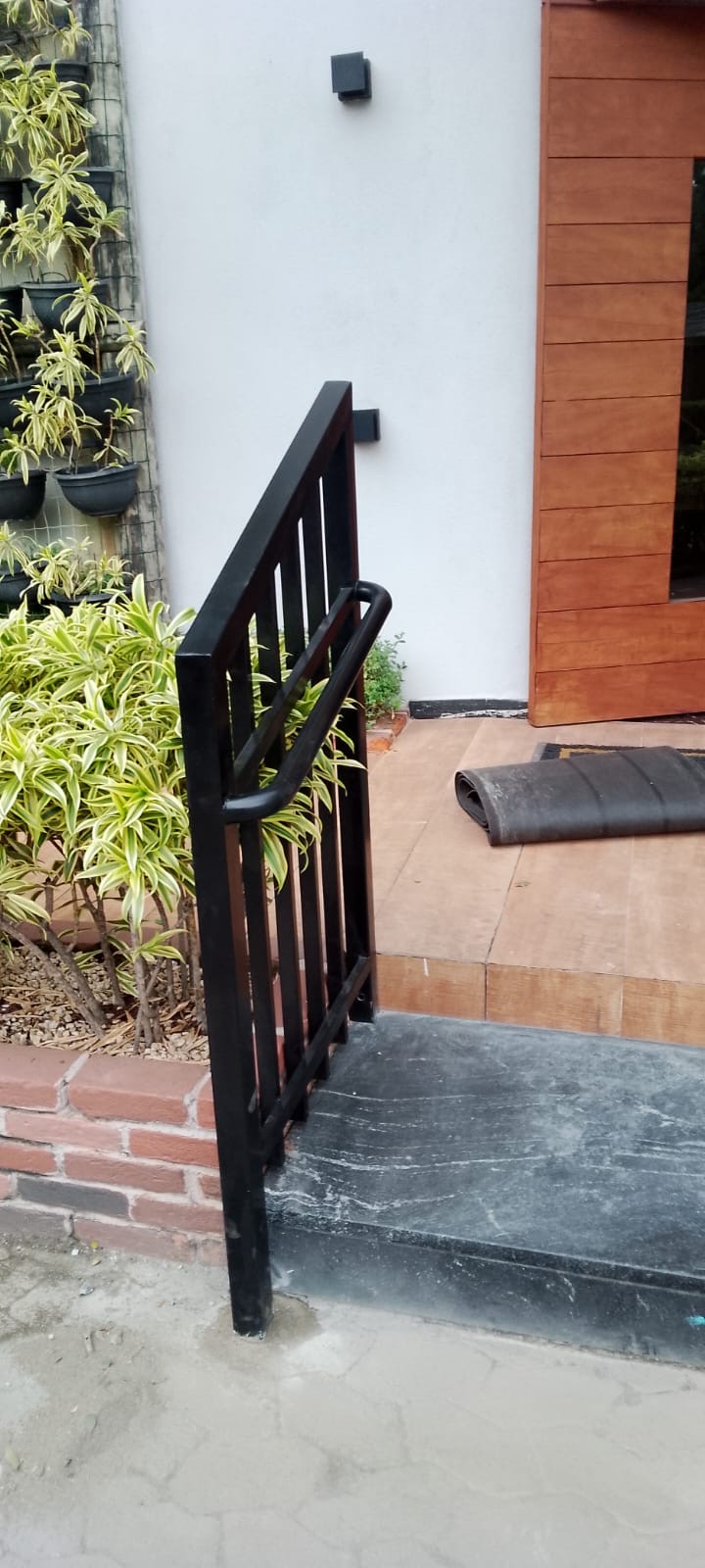 Guarda-corpo metálico preto ao lado de escada de entrada